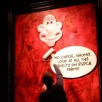 image of protestor sticking Wallace and Gromit posters to King's portrait