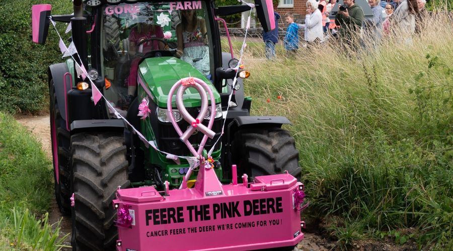 John Deere tractor at the Pink Ladies Tractor road run with sign on front reading 'Cancer Feere the Pink Deere we're coming for you'