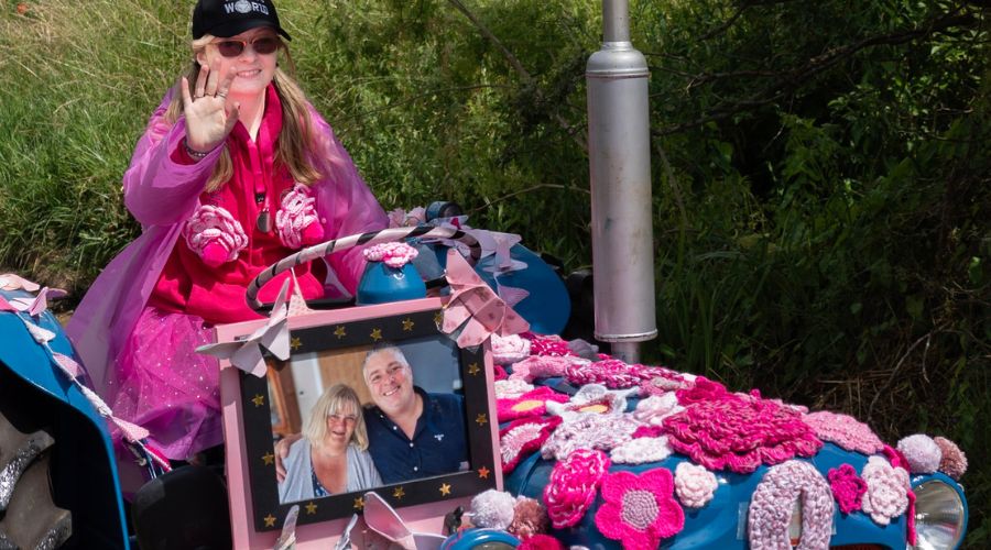 tractor decorated with knitted pink flowers, with picture of a couple on the front of the tractor, at the pink ladies tractor road run