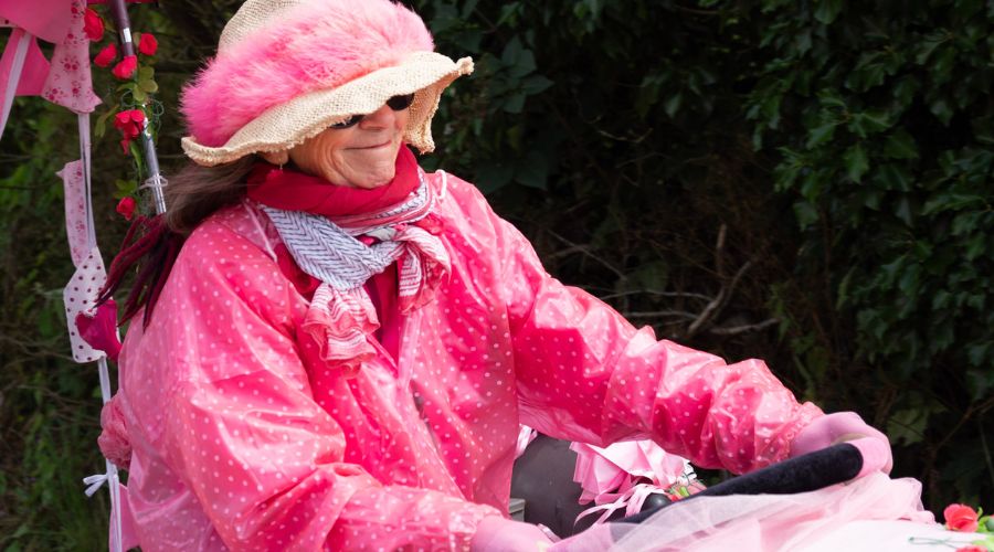 close up of woman all in pink driving a tractor at the pink ladies tractor road run