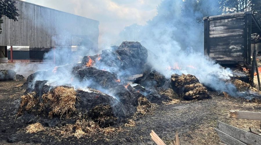 Firefighters have tackled a large hay bale blaze involving 15 tonnes of straw, a lorry and trailers on the Essex-Suffolk border. 