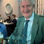 David black sitting at a table with his Farming Champion award in front of him, and other attendees of the awards ceremony in the background