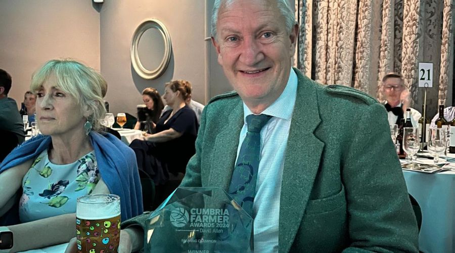 David black sitting at a table with his Farming Champion award in front of him, and other attendees of the awards ceremony in the background