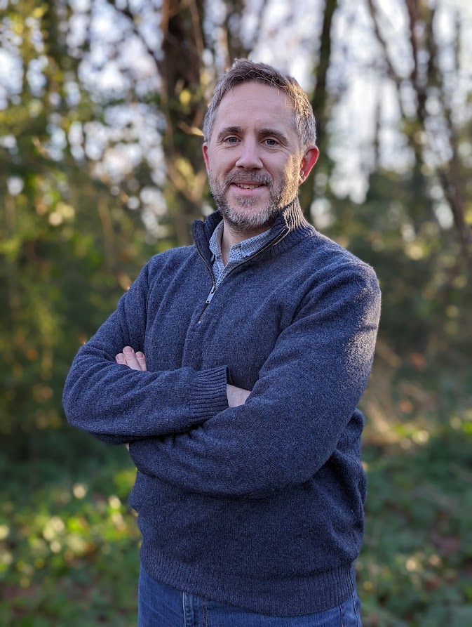 Dan Yates, pitchup.com founder standing with arms folded, trees in the background