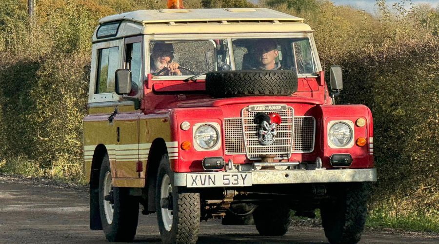 red vintage Land Rover with a skull decoration attached to the front 