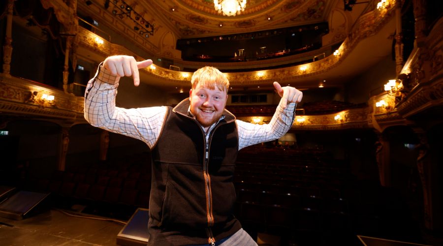 Kaleb Cooper smiling and standing in an empty theatre venue before the start of a performance during his UK tour