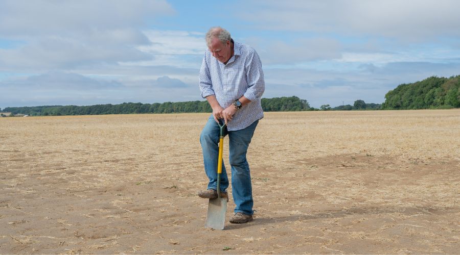 Jeremy Clarkson using a shovel to try to dig into very dry compacted ground