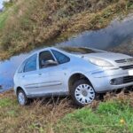 silver car parked next to a water filled ditch