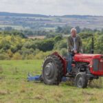 Jeremy Clarkson on red tractor in the middle of a field