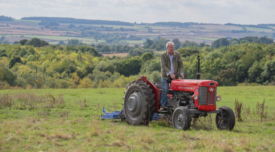 Jeremy Clarkson on red tractor in the middle of a field