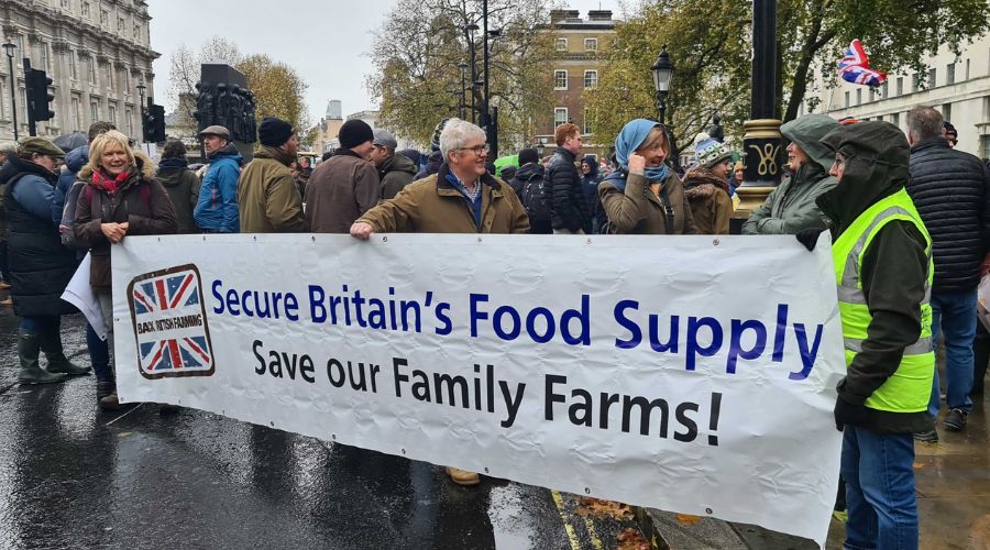 large crowd of farmers in Westminster holding banner that says 'Secure Britain's food supply. Save our family farms!'