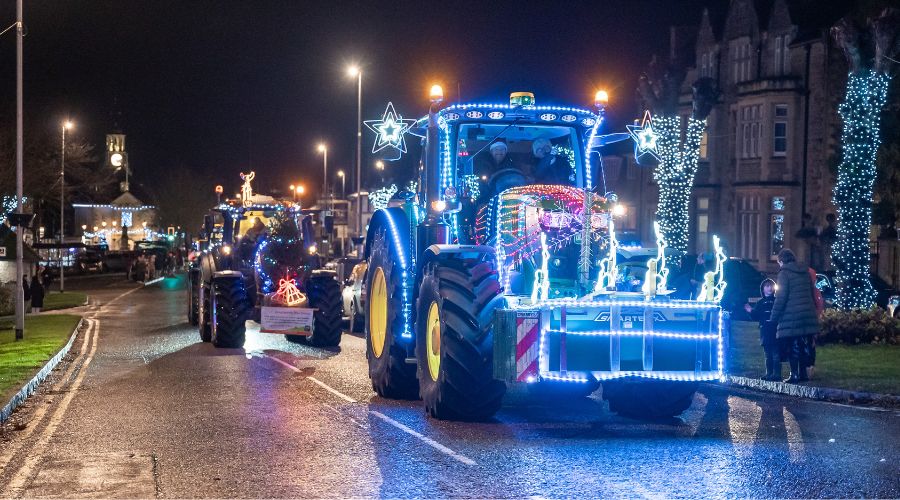 Line of tractors driving down the road, covered in lights 