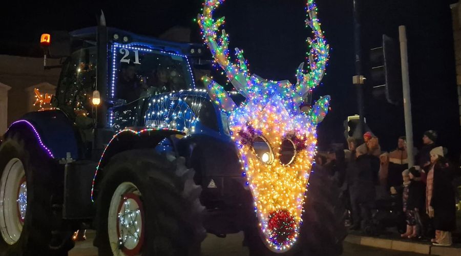 New Holland tractor with Christmas lights and a large lit up reindeer on the front 