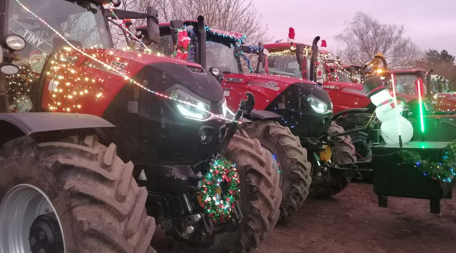 line of red tractors with festive lights and one with a light up snowman on the front