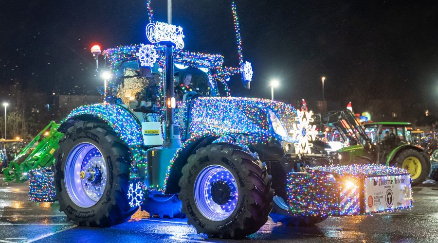 tractor covered in lights with merry Christmas sign on the top