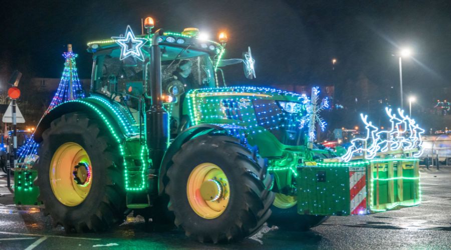 John Deere tractor with lights on it, including snowflakes, stars and a light up tree on the back, and light up reindeers on the front box