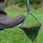 wellie boot stepping on soil testing device in the grass