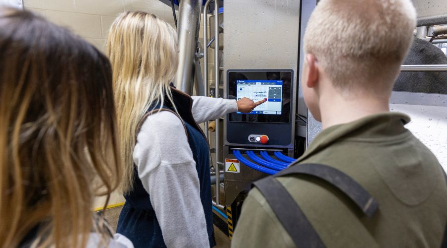 three students looking at a Delaval milking system screen